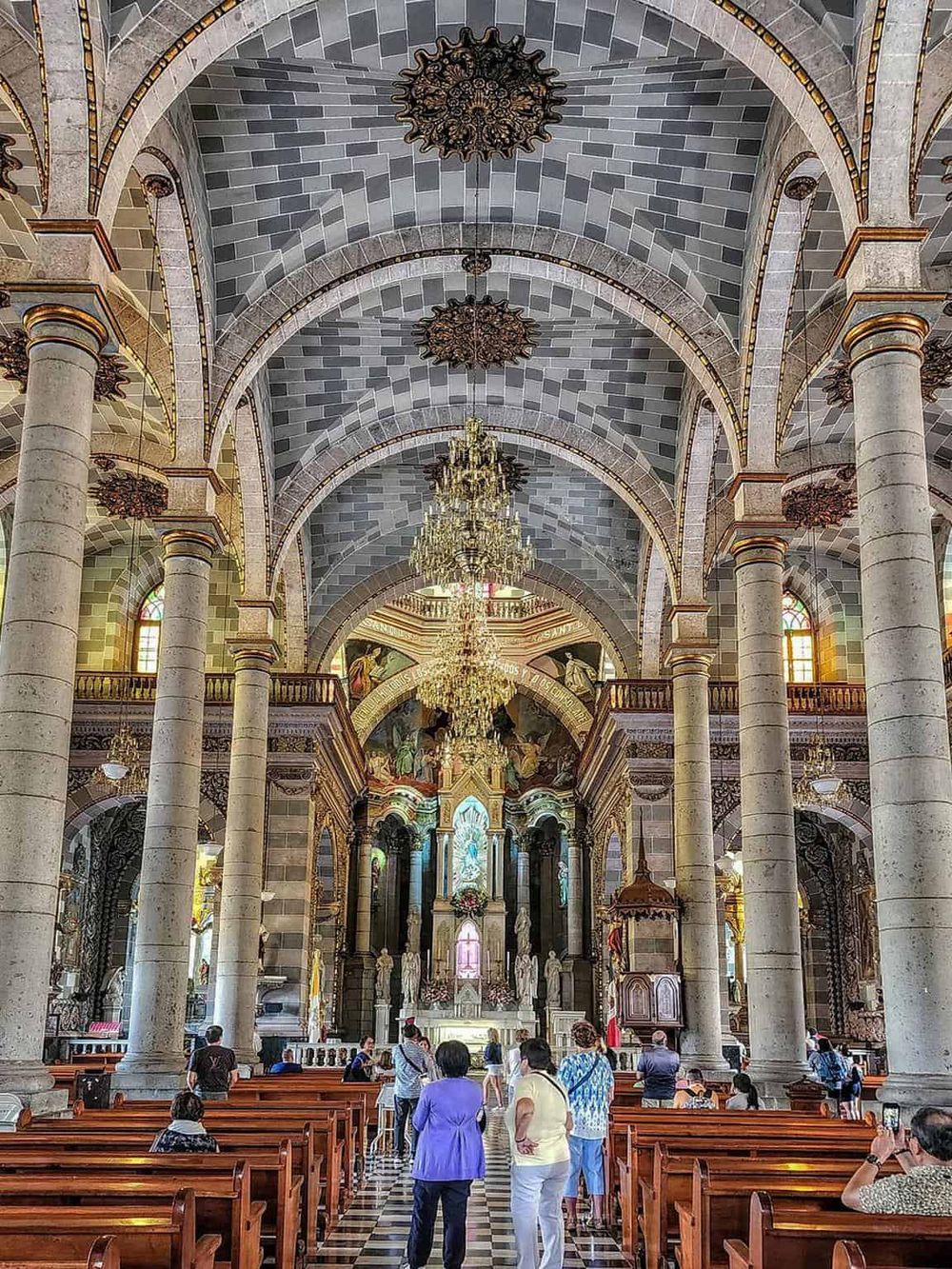 Stunning church interior featuring vaulted ceilings, ornate chandeliers, and religious statues, exemplifying architectural beauty and spiritual significance.