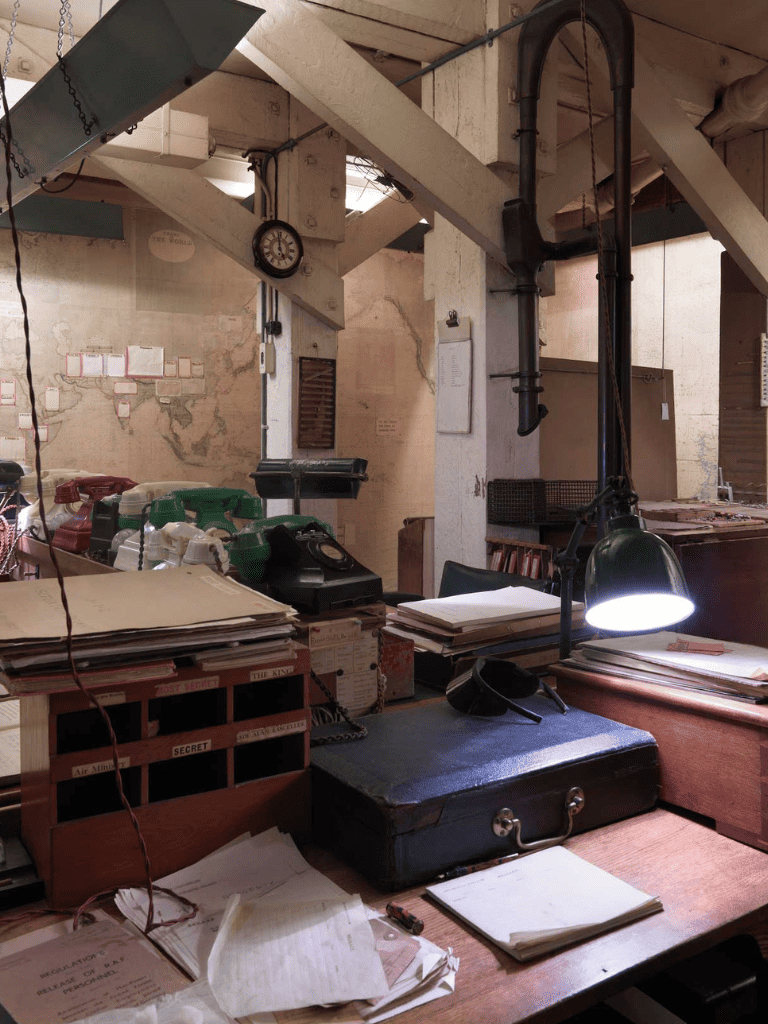 Desk with vintage phones, files, and secret file drawers in an office setting.