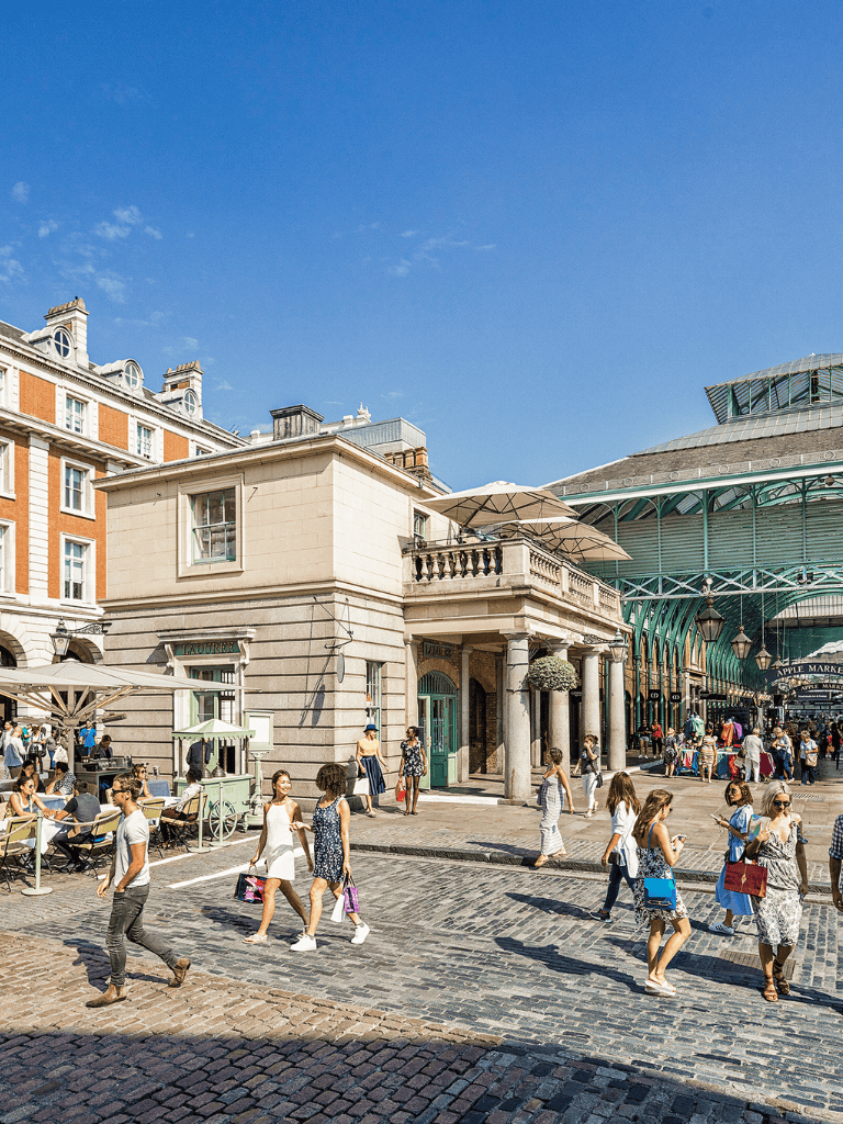 Bustling city street with shoppers, historic architecture, and vibrant market atmosphere.