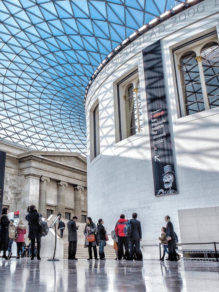 Architectural glass roof interior of the British Museum in London, showcasing modern design and visitors exploring exhibits.