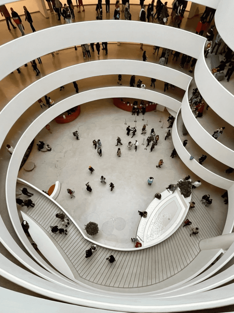 Interior view of a modern multi-level mall with people walking around and escalators connecting different floors.