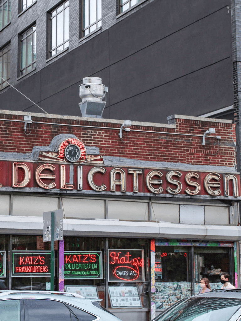 Delicatessen store with neon signs and urban street view.