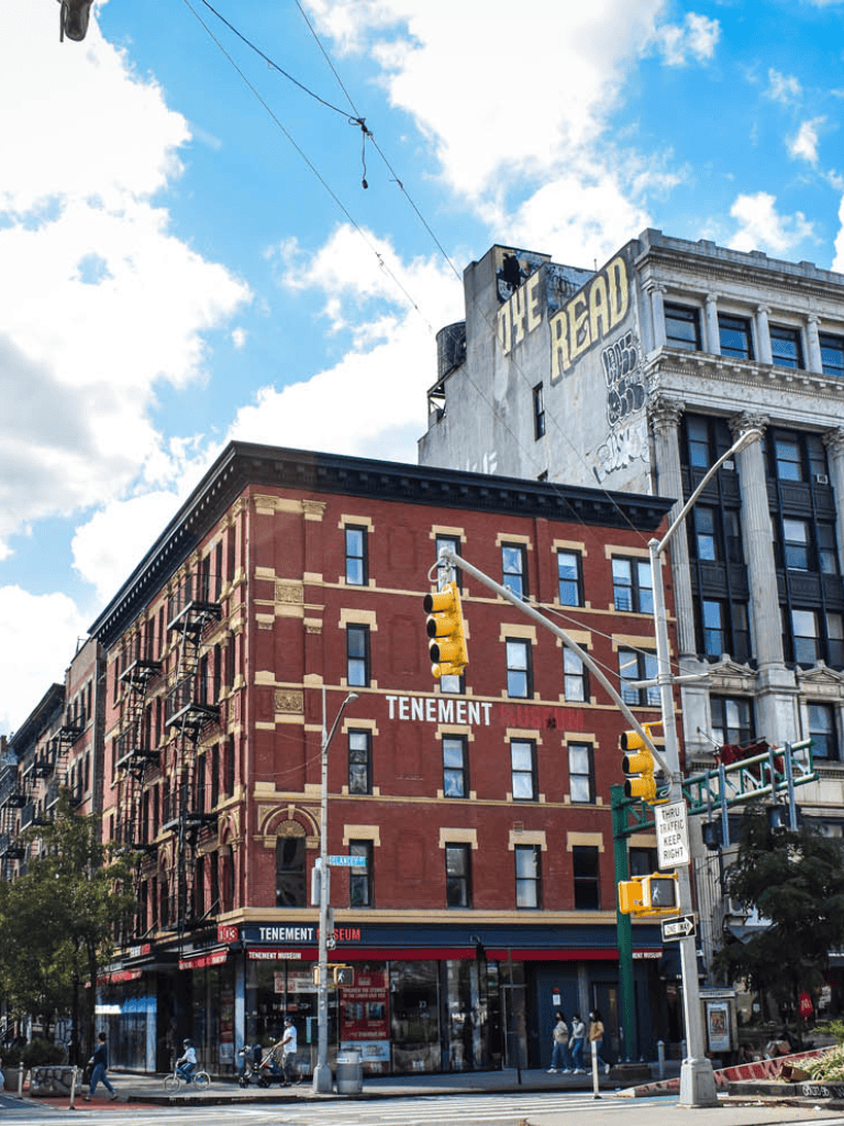 Historic red brick building with Tenement Museum signage in urban city street scene.