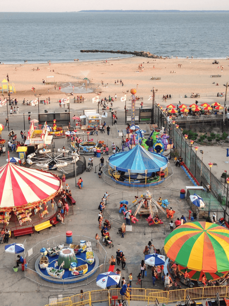 Brightly lit amusement park at the beachside featuring rides, games, and colorful attractions under sunny skies.