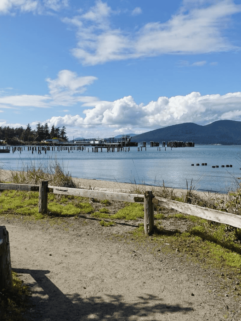 Tranquil waterfront with pier, mountain view, and sandy beach in Oregon.