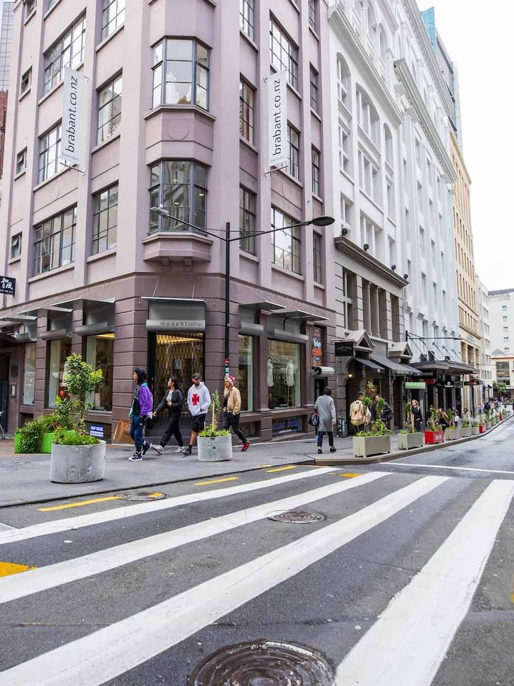 Bright city street with pedestrians, modern buildings, and colorful storefronts in downtown.