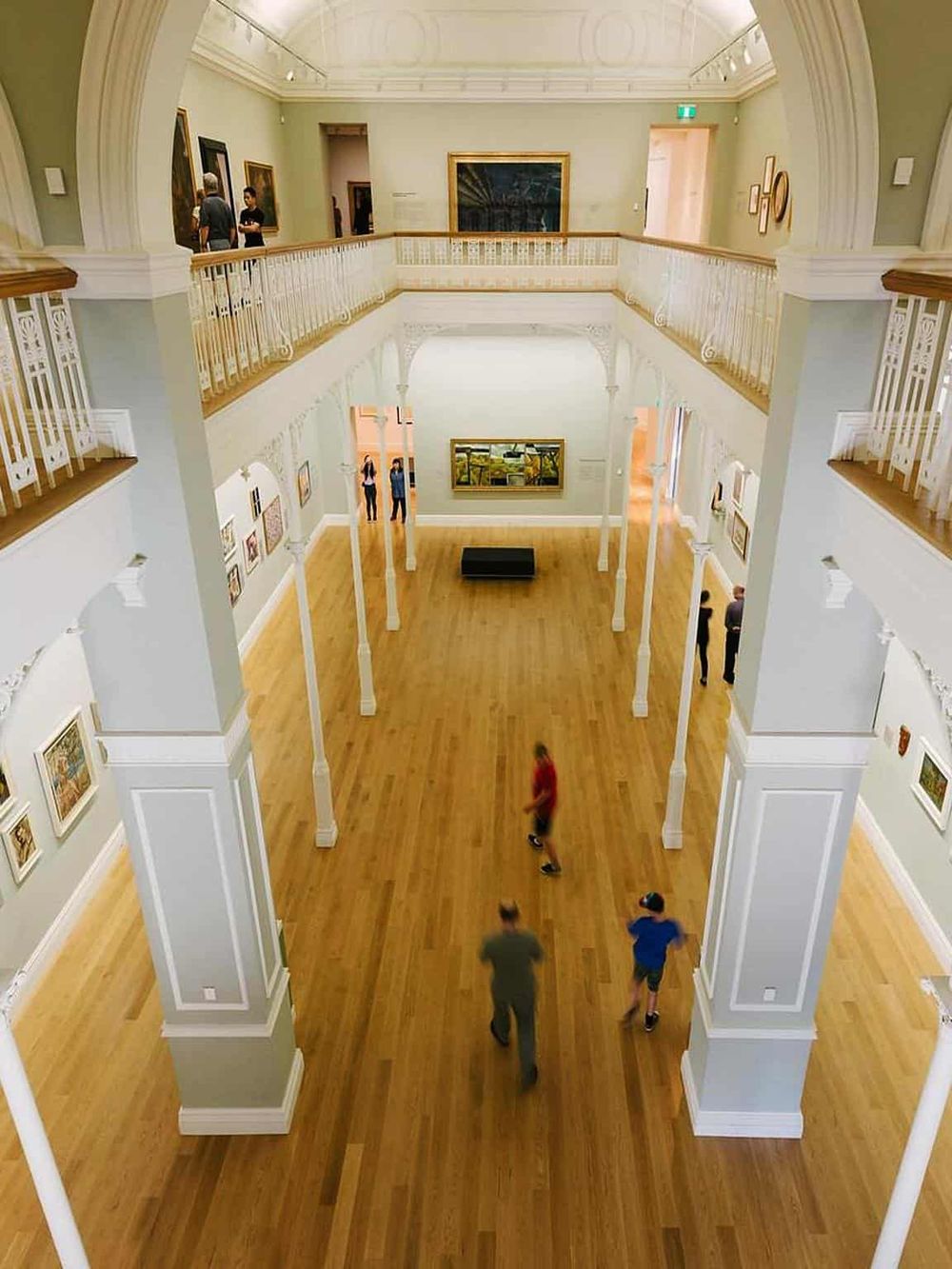 Colorful art gallery interior with visitors exploring exhibits, showcasing museum navigation and tour experience.