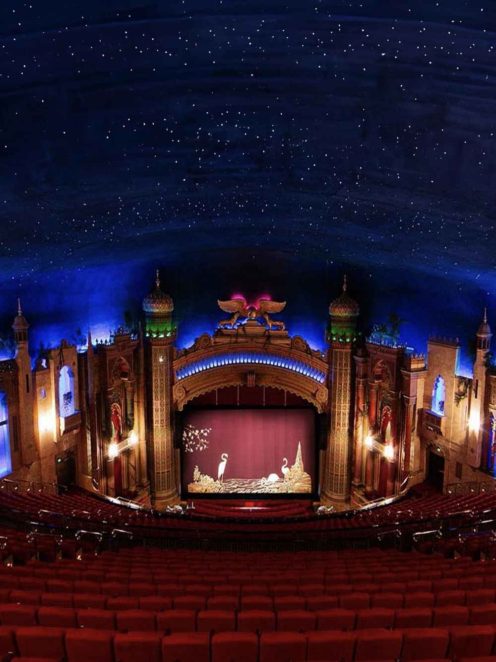 Vibrant theater interior with detailed Asian-inspired architecture, starry sky ceiling, and colorful lighting.