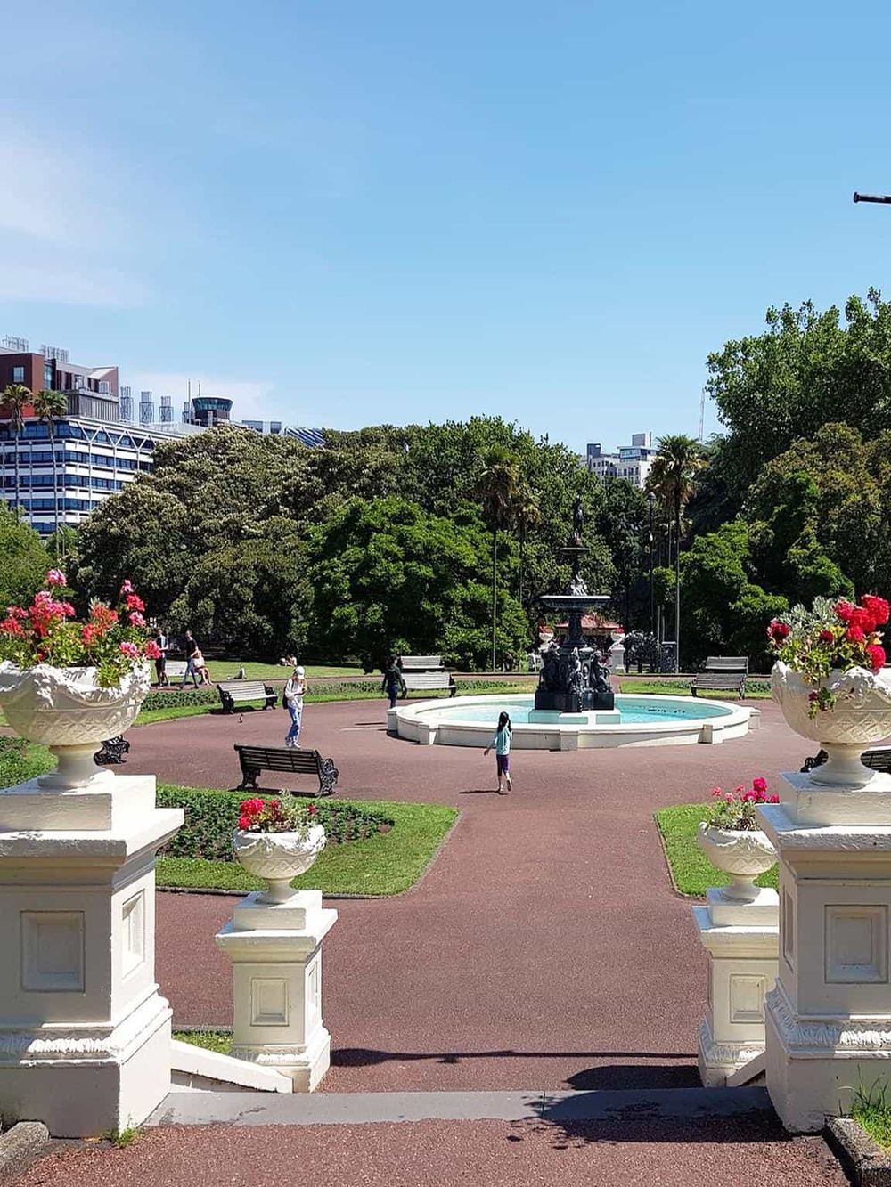 Colorful city park with fountain, lush trees, and vibrant flowers, perfect for sightseeing and leisure activities.