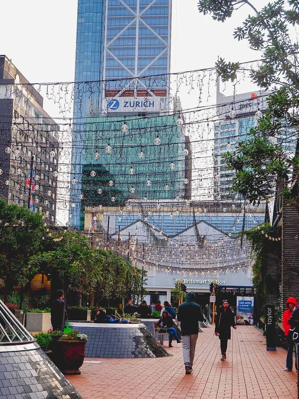 Colorful urban shopping district with string lights and modern high-rise buildings in the background.