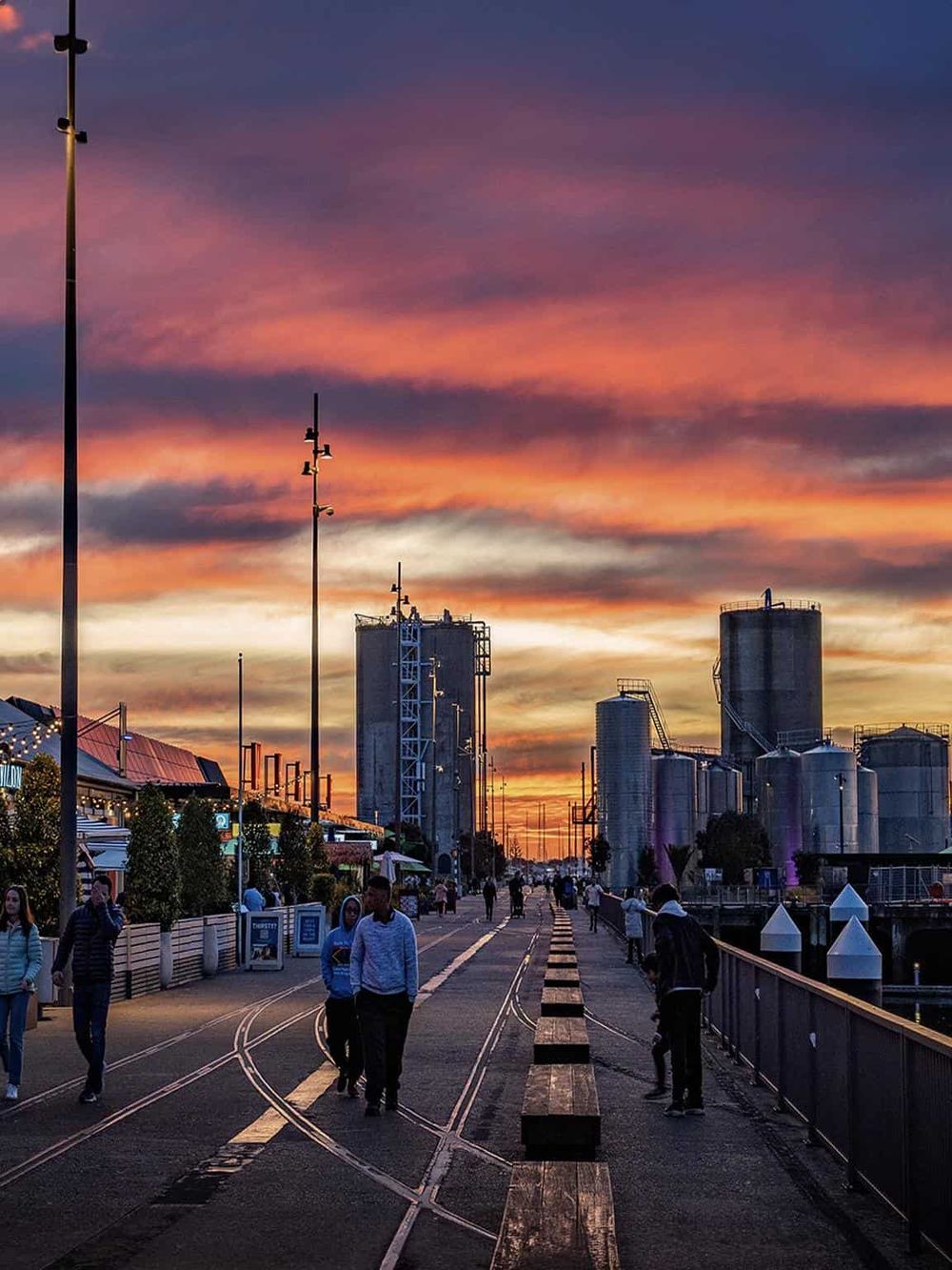 Vibrant cityscape at sunset with industrial buildings and walking pedestrians, highlighting urban navigation and directions.