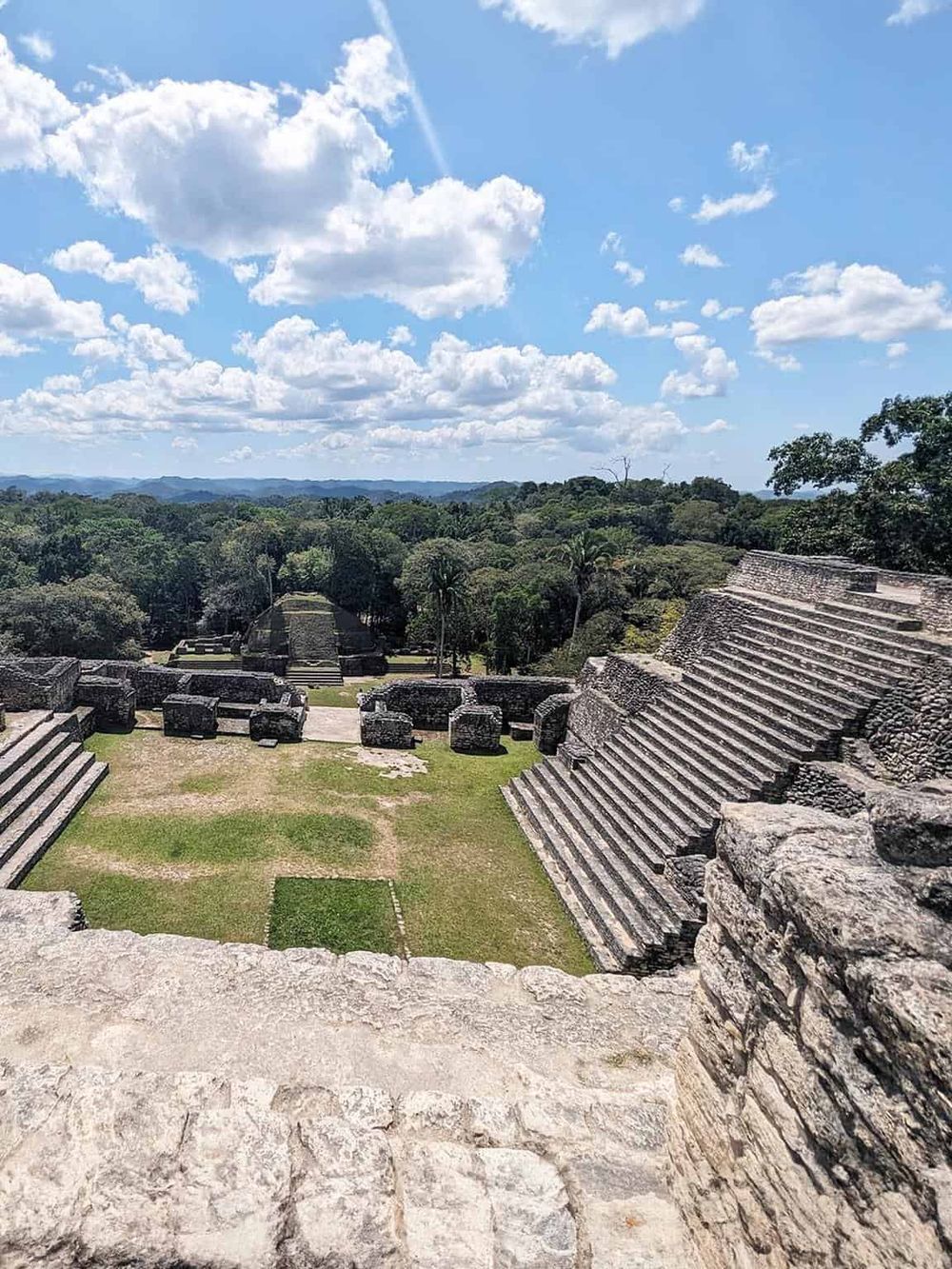 Ancient Mayan ruins at a historic archaeological site with lush green jungle background and clear blue sky.