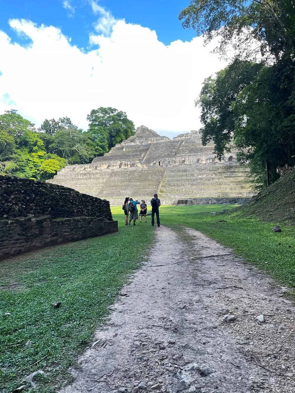 Ancient Mayan pyramid at Tikal with tourists exploring the site surrounded by lush jungle.