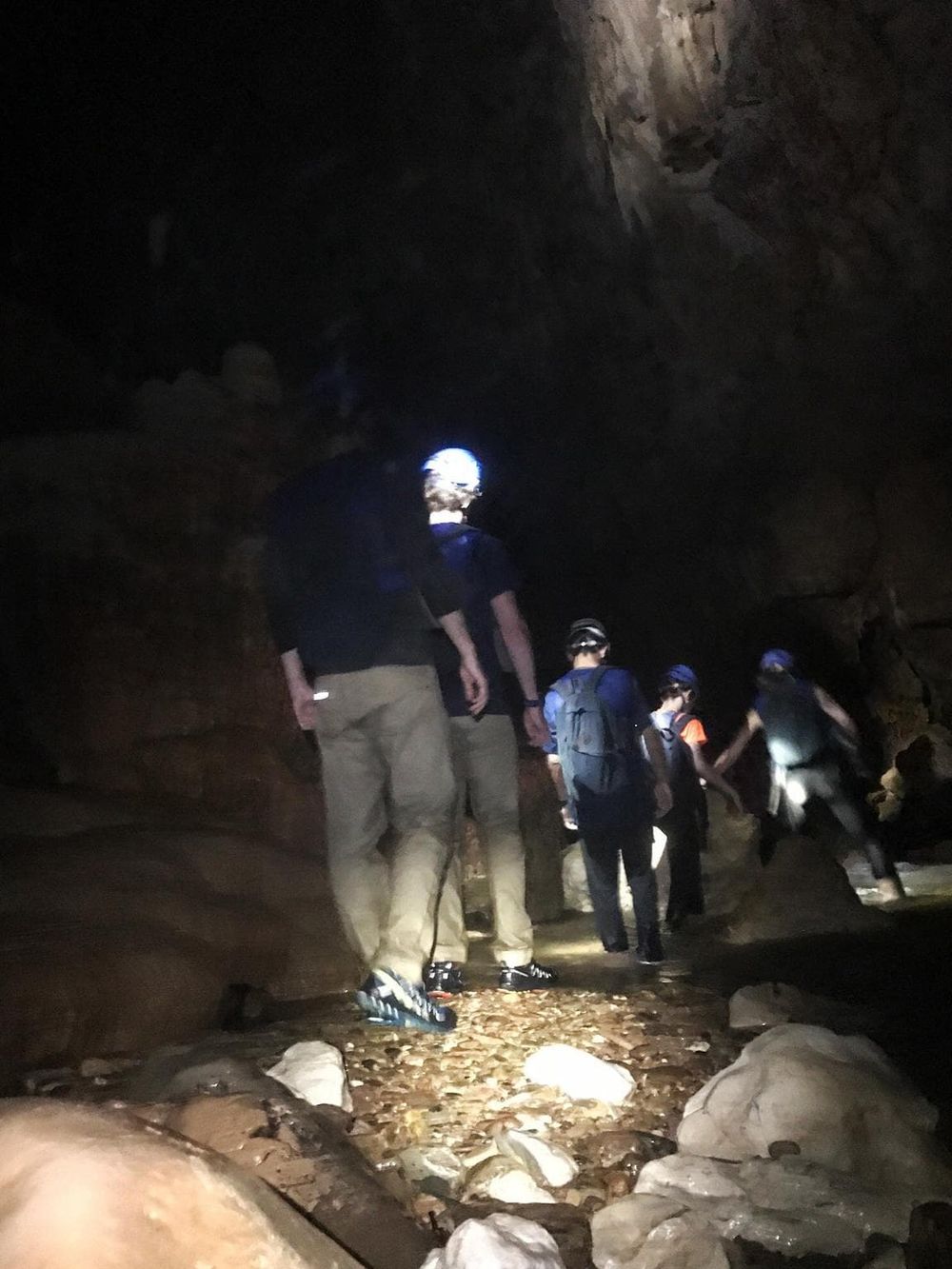 Exploring a dark cave with a group of adventure seekers wearing helmets and flashlights.