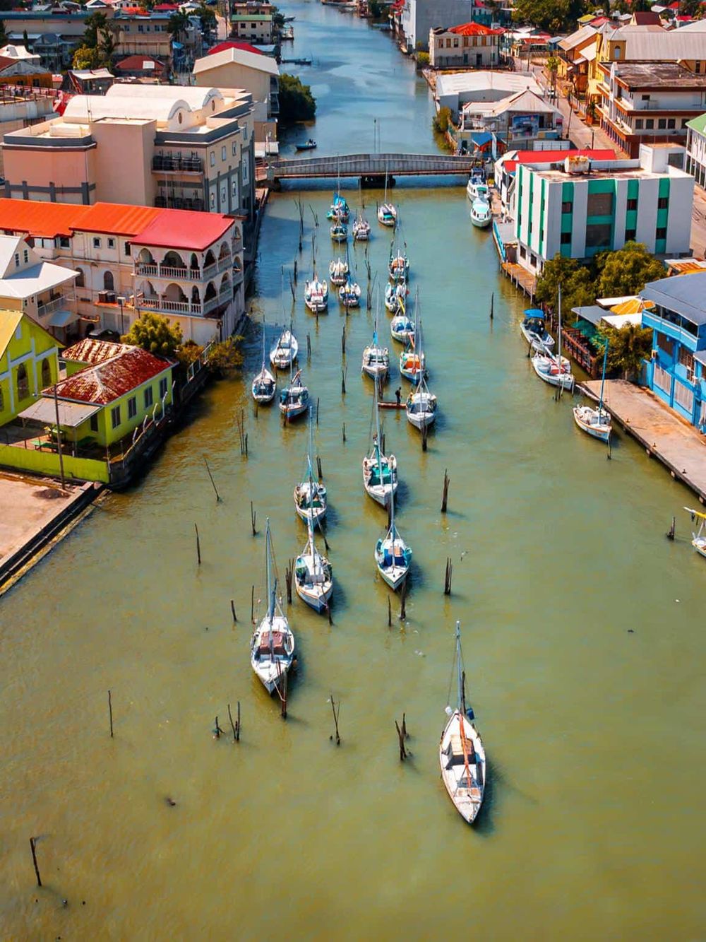 Colorful harbor with sailboats docked along a picturesque waterway in a vibrant coastal town.