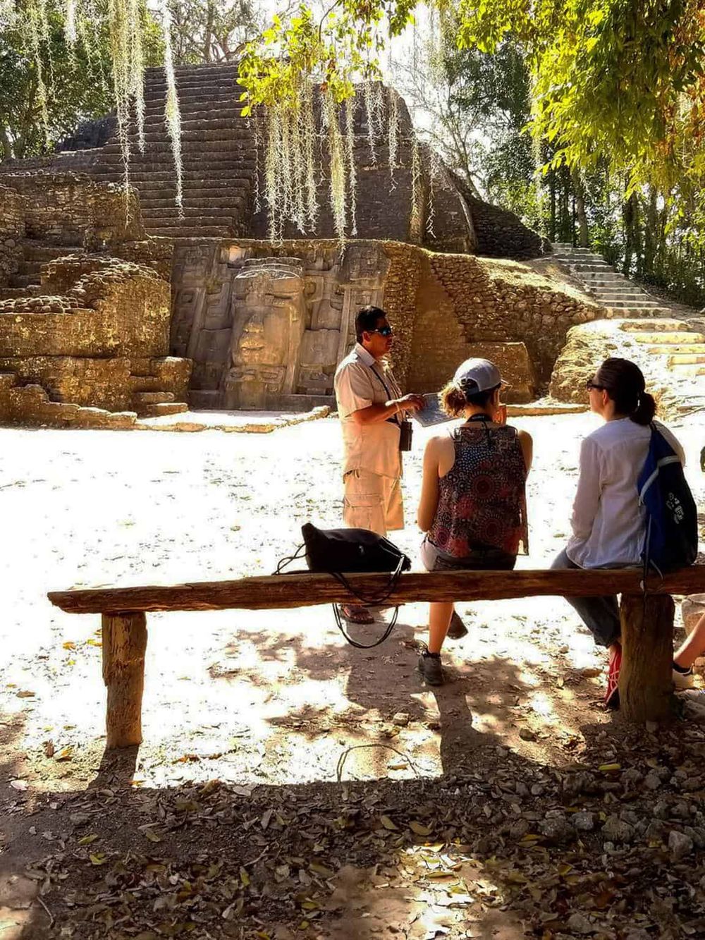 Ancient Mayan ruins tour with guide explaining history to visitors in a lush jungle setting.