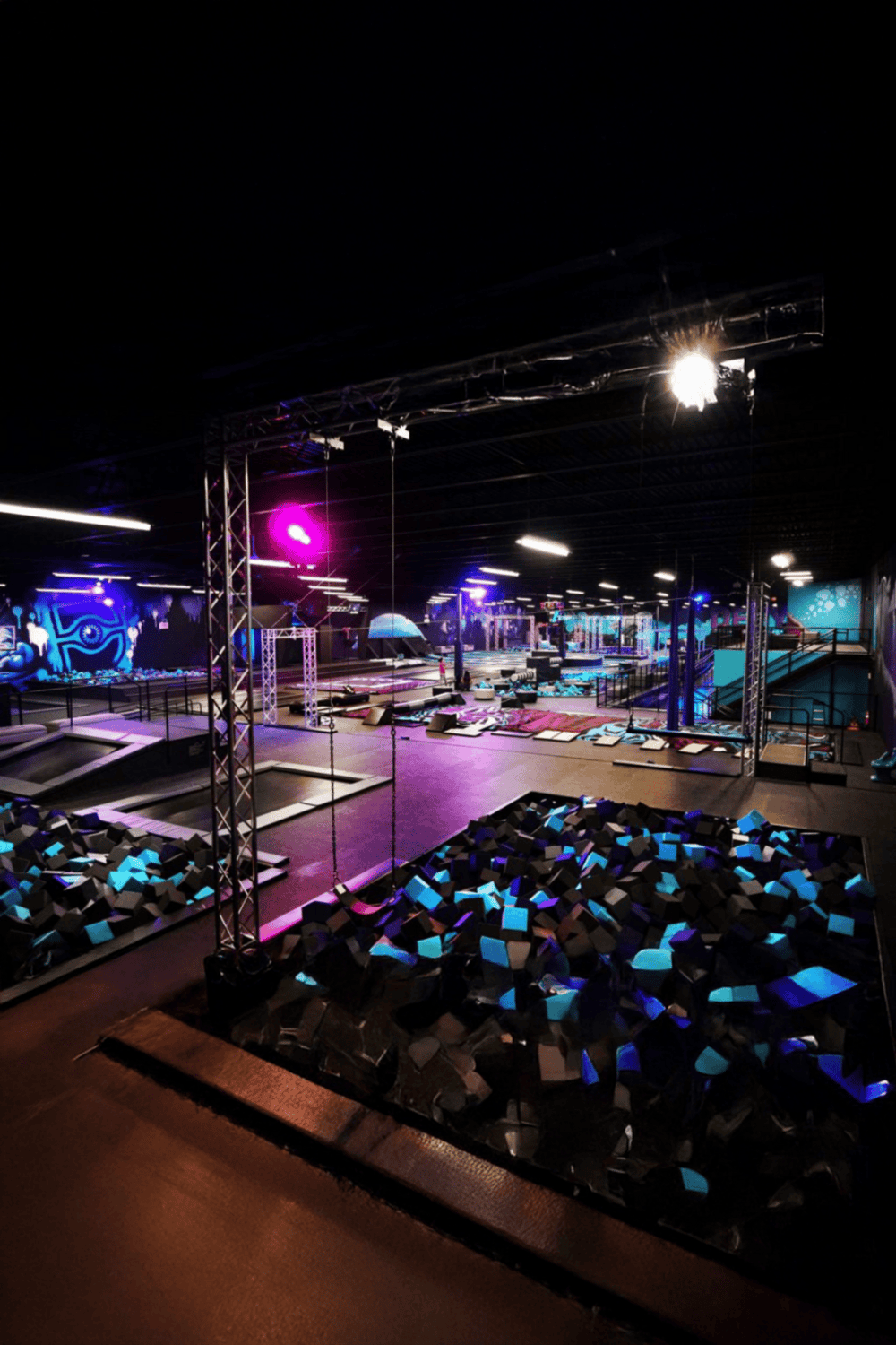 Glow in the dark trampoline park with vibrant LED lighting and foam pits for kids and adults.