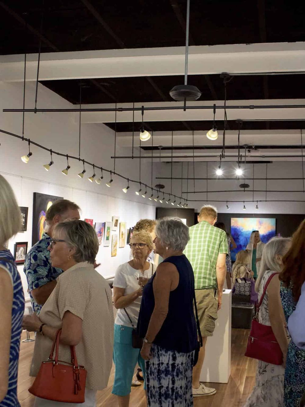 Colorful art gallery exhibit at QuestForDirections, showcasing diverse artwork in a well-lit, modern space.