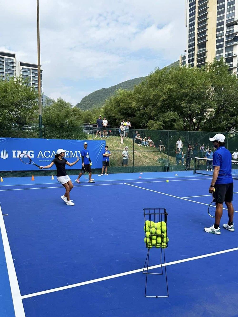 Tennis training session at IMG Academy with players practicing on vibrant blue courts.