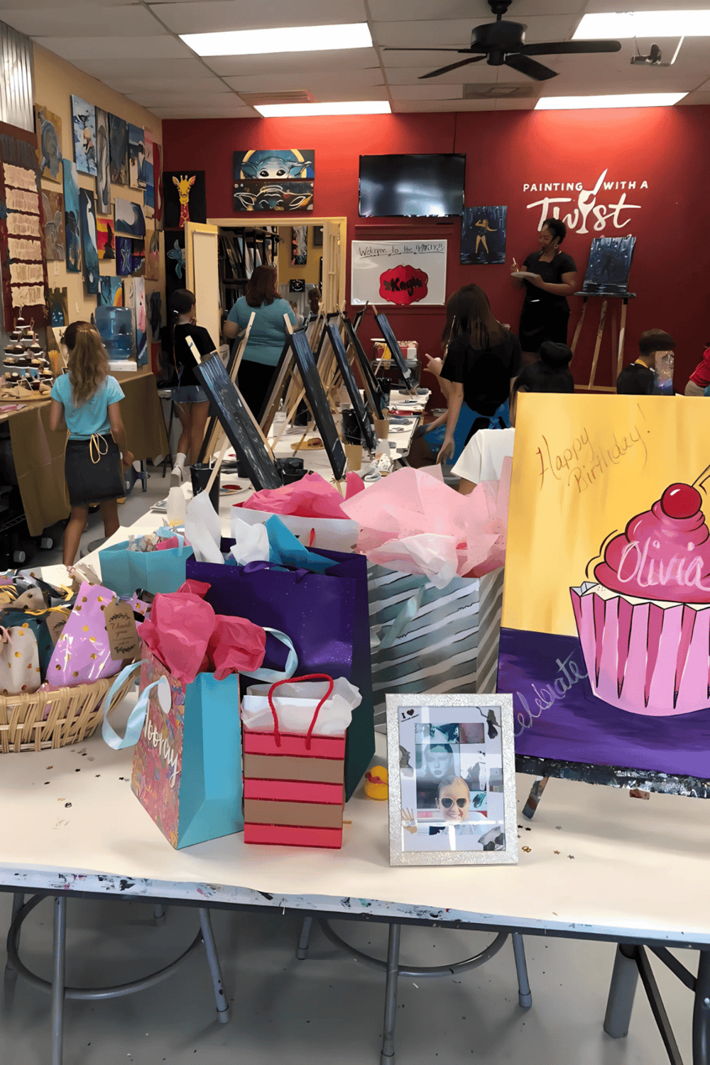 Heart-shaped birthday cake with pink frosting and "Olivia" written on it, birthday gifts, and celebration setup at Quest for Directions.