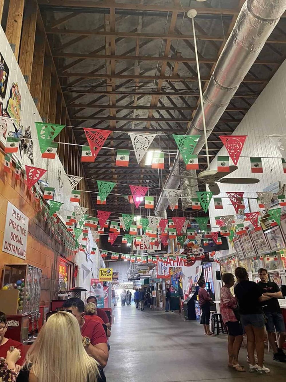 Colorful Mexican flags and decorations in a lively indoor marketplace.