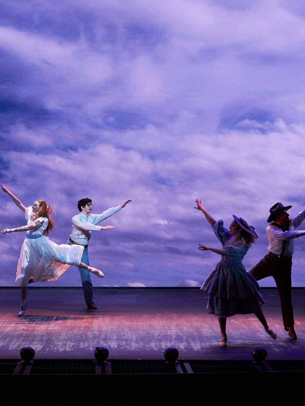 Elegant dance performance on stage with vibrant costumes and dramatic background.