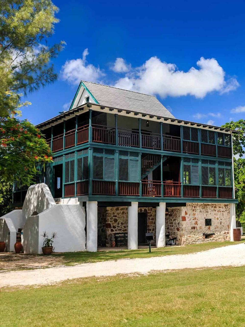 Charming multi-story vacation home with spacious porch nestled in lush greenery under a bright blue sky.