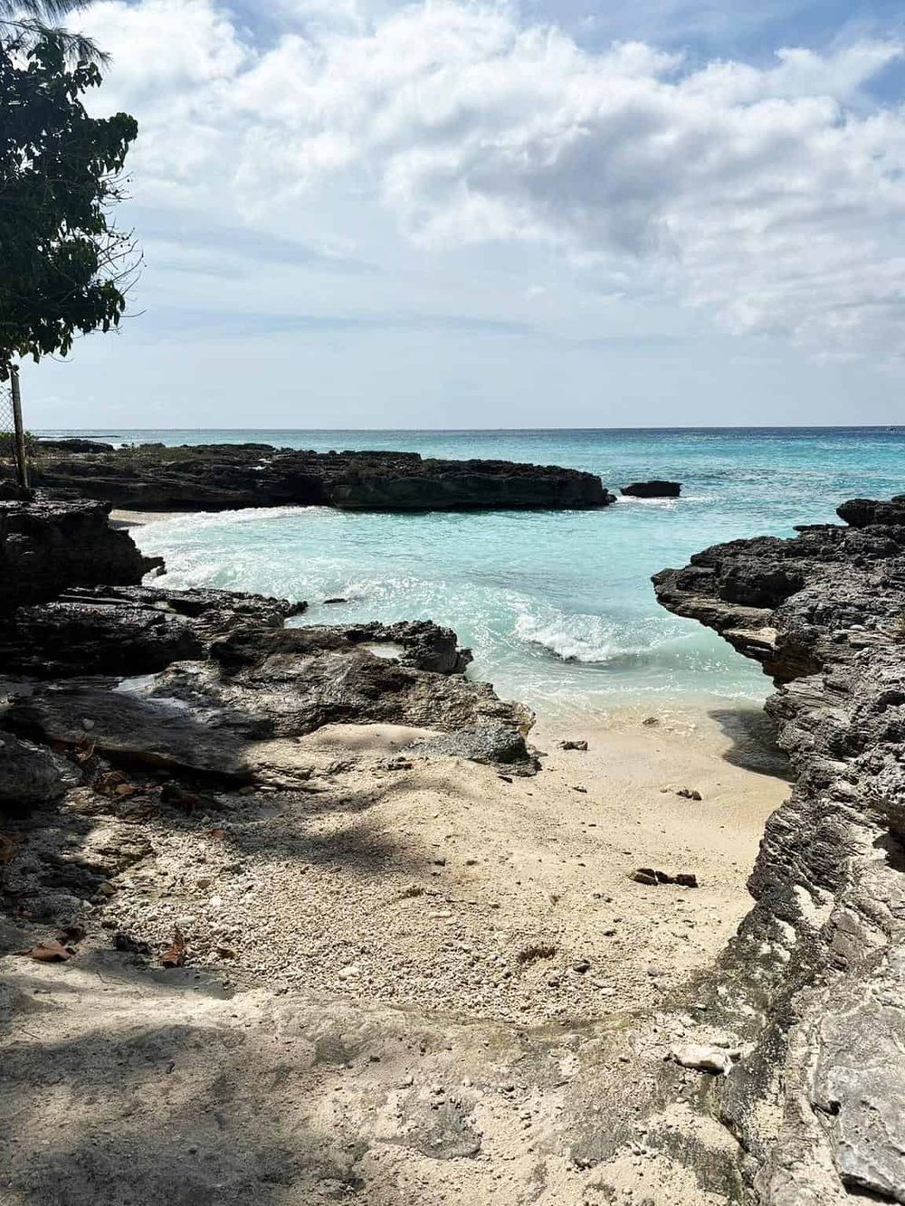 Tranquil ocean cove with rocky shoreline, sandy beach, and clear blue water, perfect for a peaceful coastal escape.