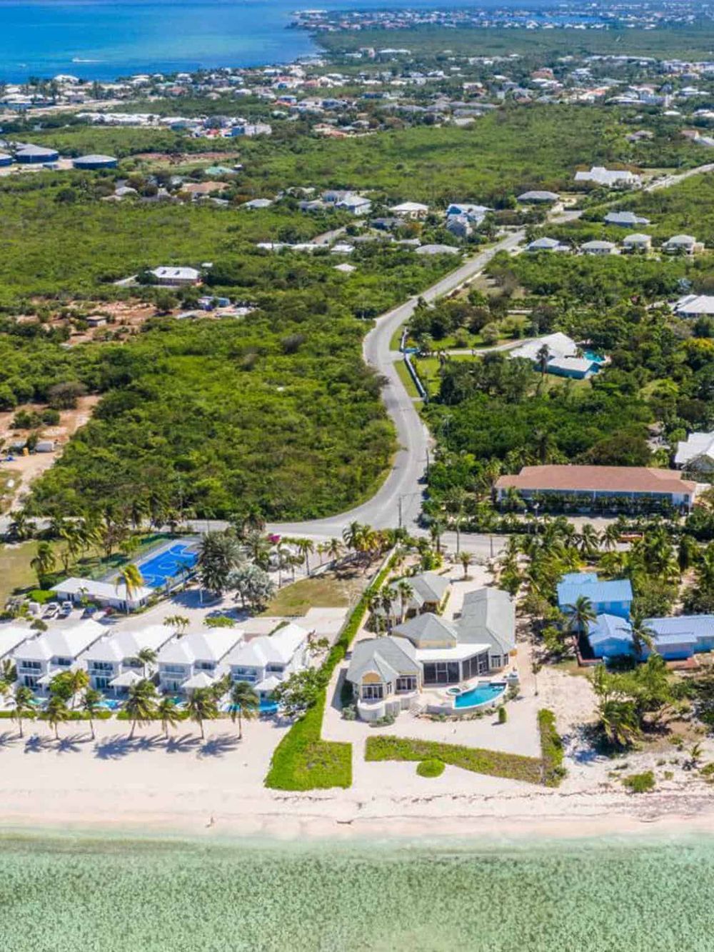 Luxury beachfront vacation homes with pools in a tropical coastal setting.