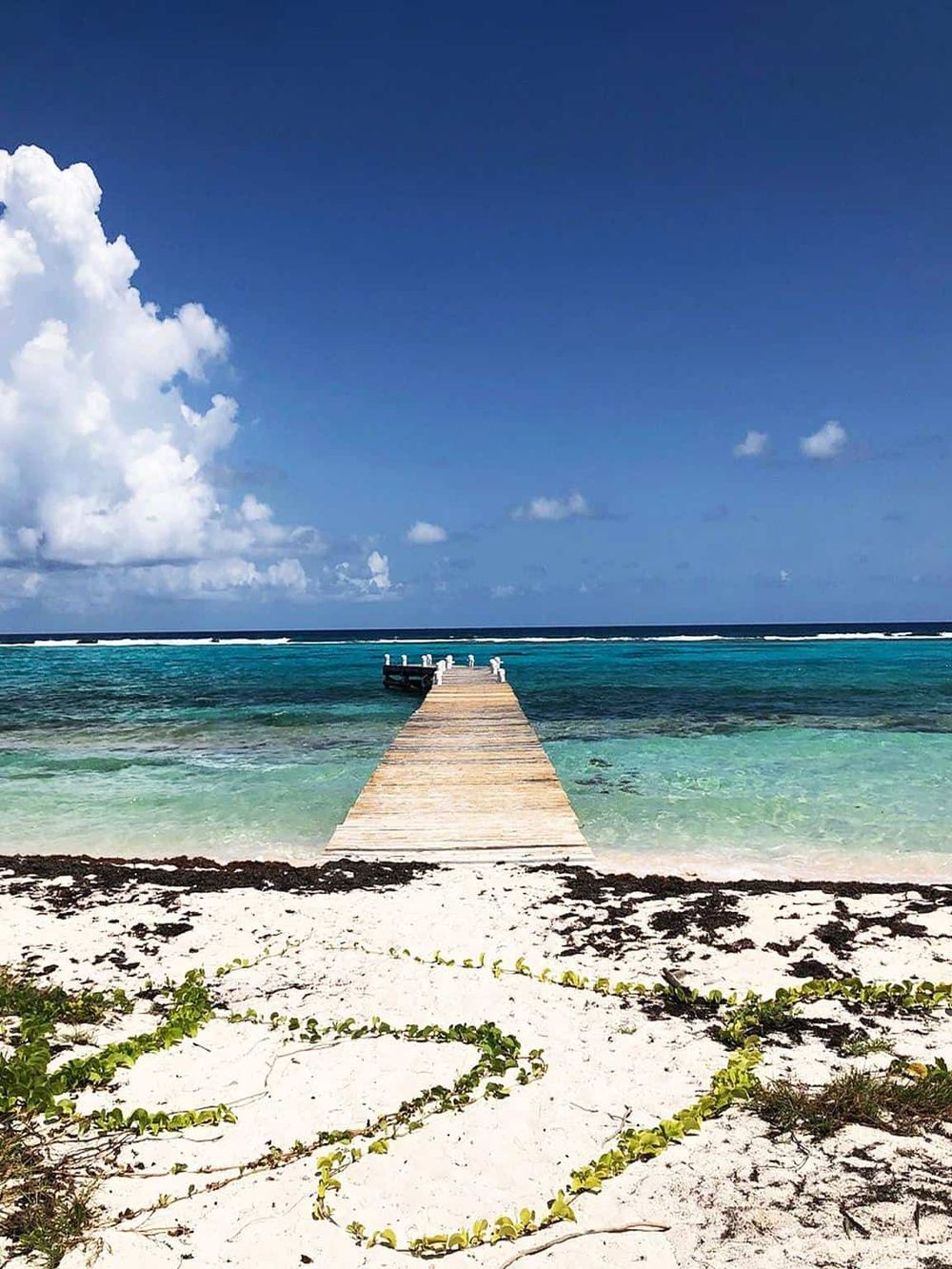 Serene tropical ocean pier at sunset, stunning clear water, blue sky, perfect for vacation.