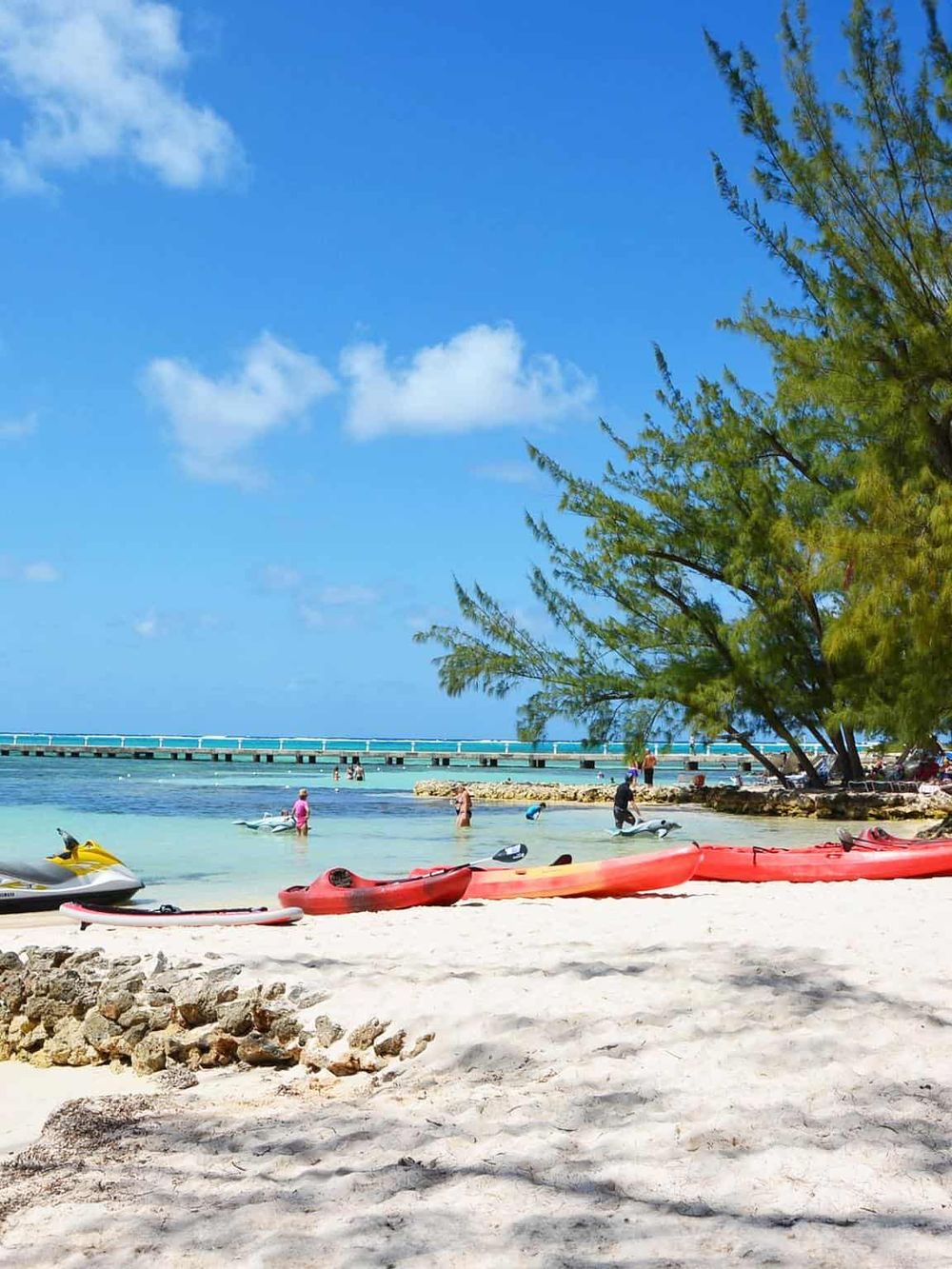 Vibrant beach scene with kayaks, paddleboards, and clear turquoise water at Quest for Directions.