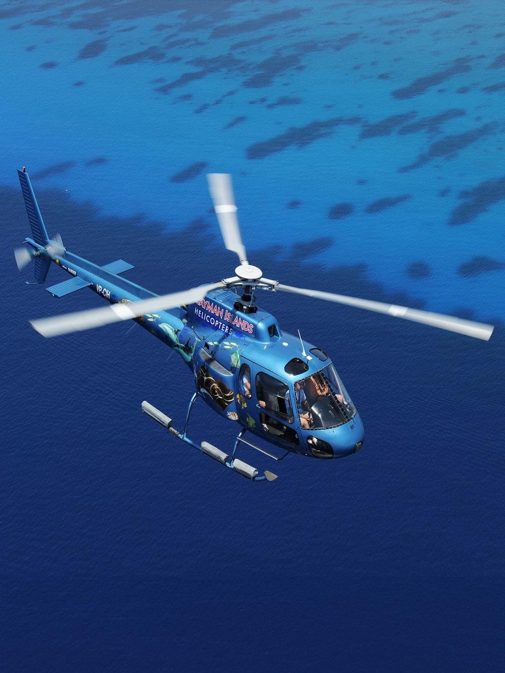 Colorful helicopter flying over ocean waters, showcasing adventure and travel experiences.