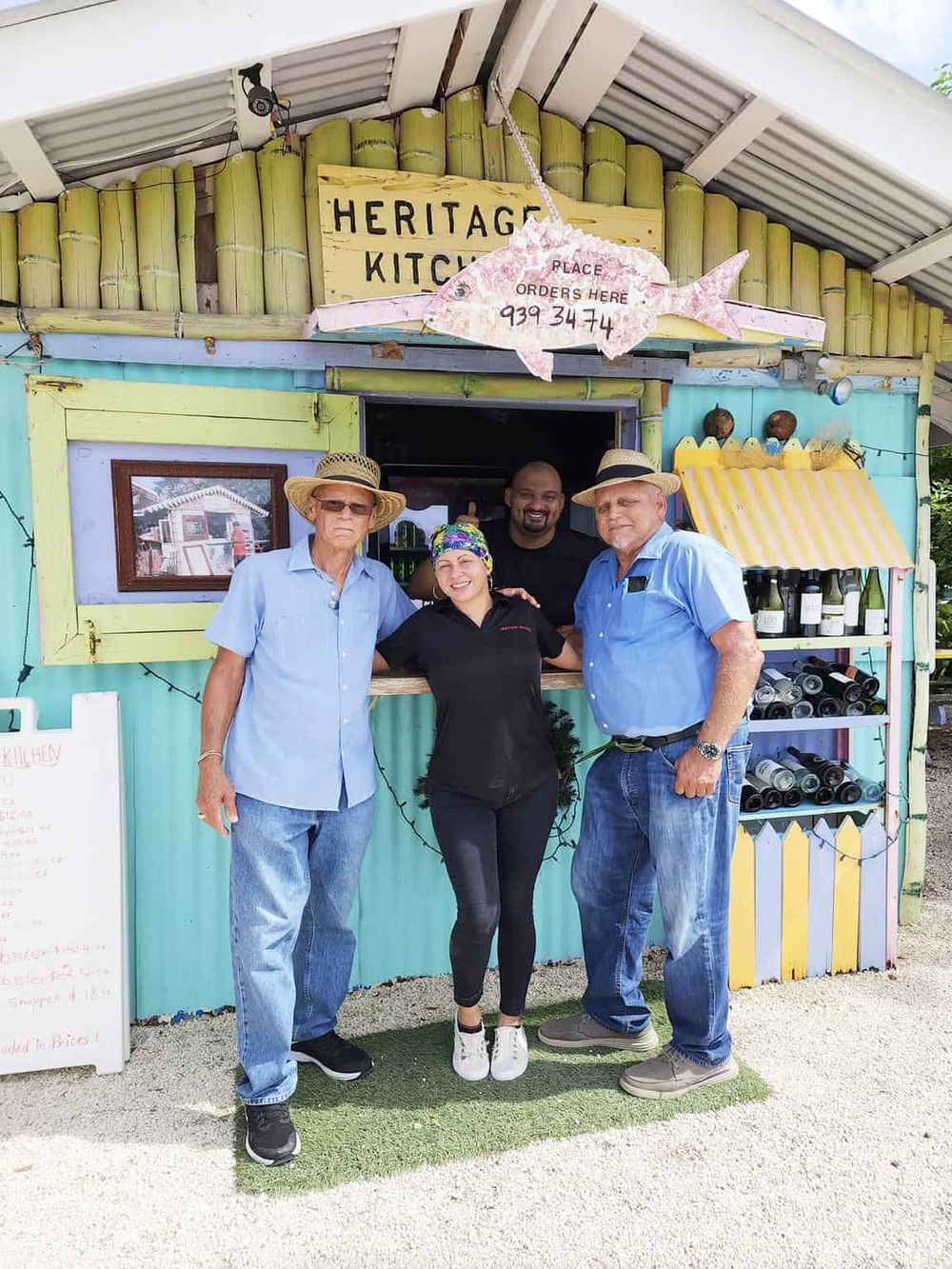 Colorful heritage kitchen food stall with staff posing for photo, vibrant outdoor setting, popular local eatery, delicious seafood options.