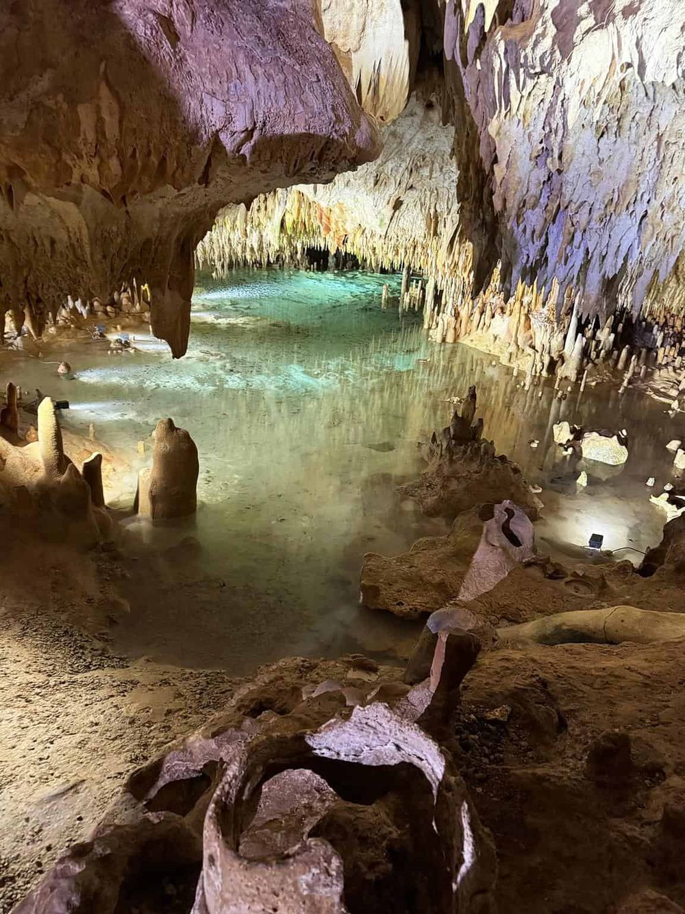 Stalactite cave with underground pool, vibrant lighting, and unique rock formations for adventurous exploration.