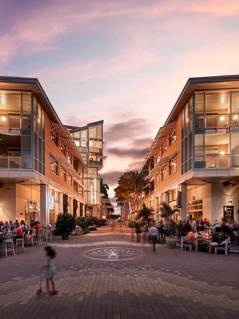Charming outdoor shopping and dining area with modern architecture, palm trees, and twilight sky at QuestForDirections.