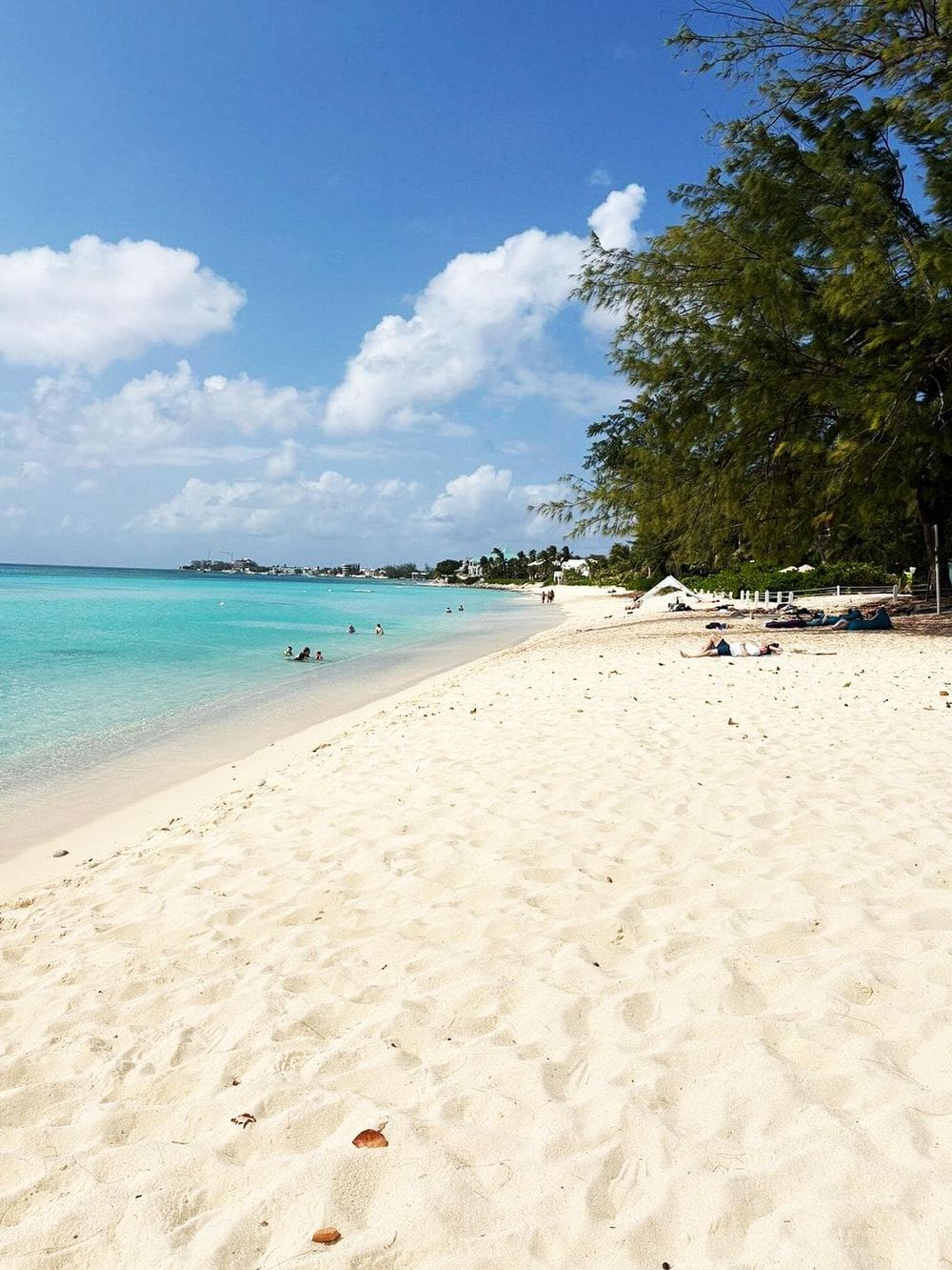 Pristine beach with turquoise waters, white sand, and lush greenery, perfect for relaxation and seaside activities.
