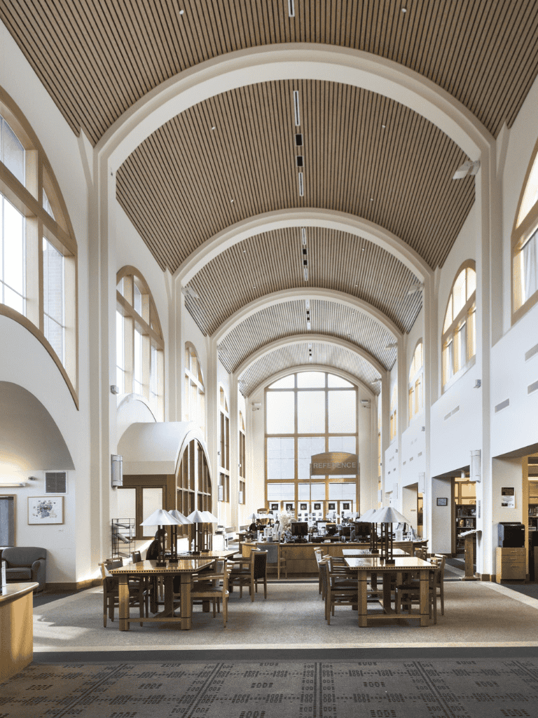 Spacious modern library interior with high arched wooden ceilings and large windows for natural light.