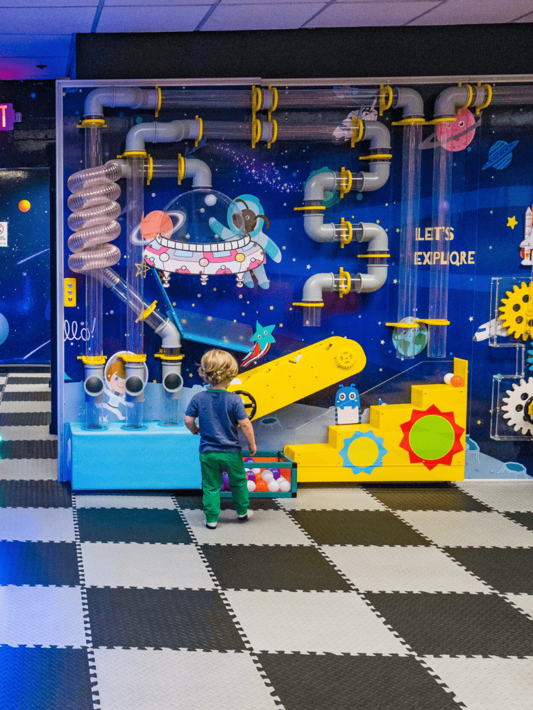 Colorful kids' space-themed interactive play area with pipes, gears, and a UFO exhibit for exploration and learning.