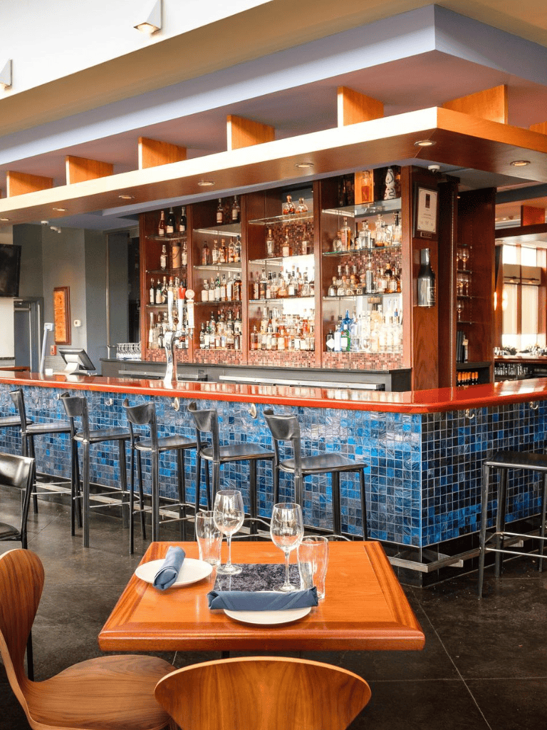 Luxurious bar interior with whiskey collection, modern seating, and upscale dining ambiance.