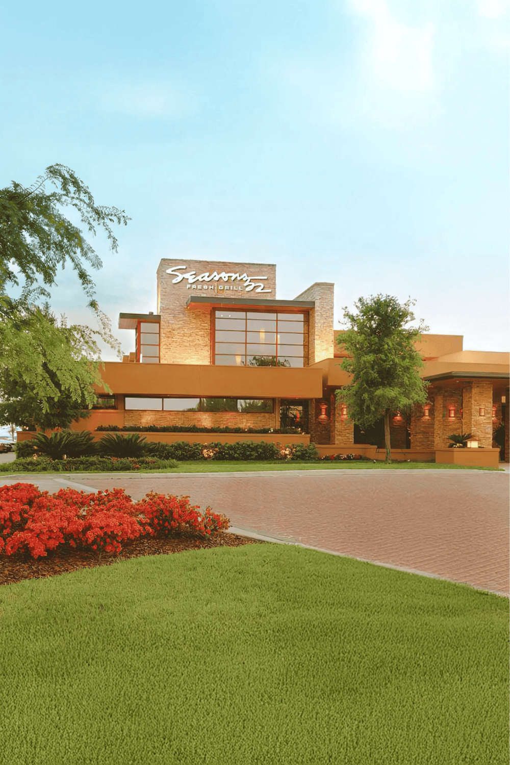 Modern restaurant building with greenery and flowers, exterior shot.