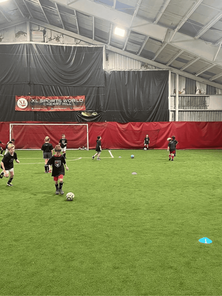 Youth soccer practice inside indoor sports facility with kids drills and training.