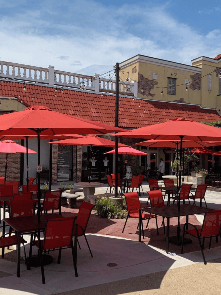 Outdoor dining area with red umbrellas and chairs, inviting atmosphere for restaurants or cafes.