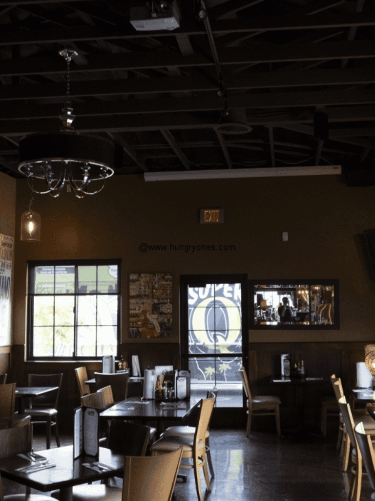 Indoor restaurant dining area with tables and chairs, ambient lighting, dark ceiling, window view, and modern decor.