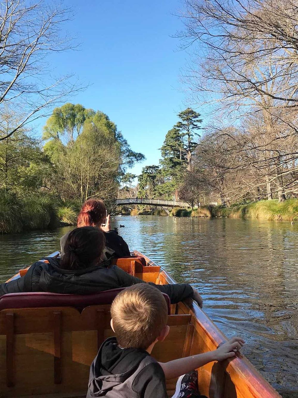 Serene boat ride on a river through lush green park with autumn trees and clear blue sky, outdoor scenic tour at QuestForDirections.