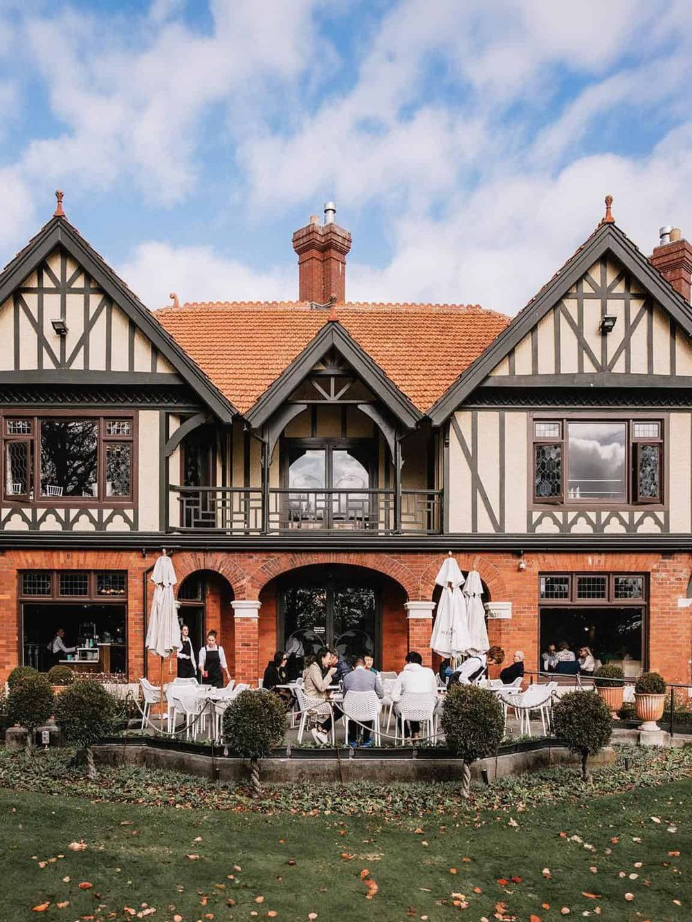 Charming Tudor-style restaurant with outdoor patio and diners enjoying meals. Perfect for food lovers and local dining experiences.