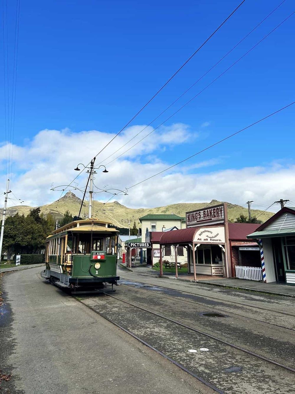 Vintage tram on historic street in Queenstown New Zealand with scenic mountains in background.