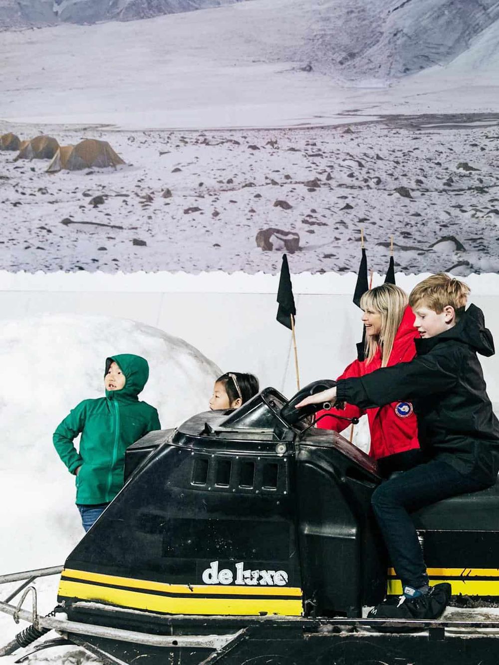 Children riding snowmobile at QuestForDirections, adventure tour in winter landscape.
