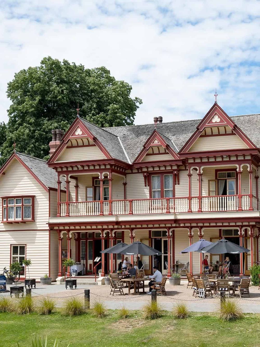 Victorian-style bed and breakfast with outdoor seating, lush greenery, and classic architecture.