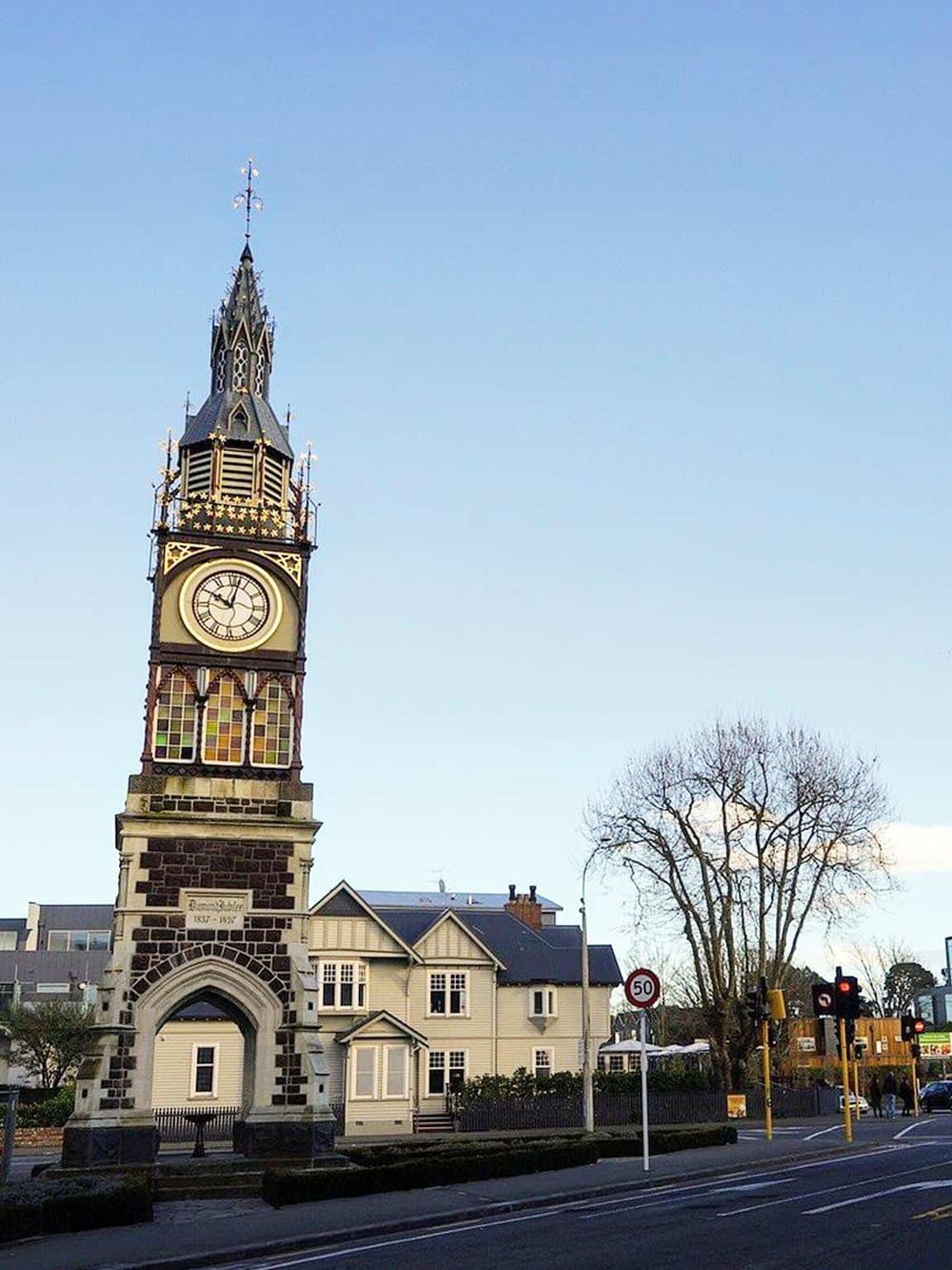 Colorful clock tower in a charming town setting with historic buildings and clear blue sky.