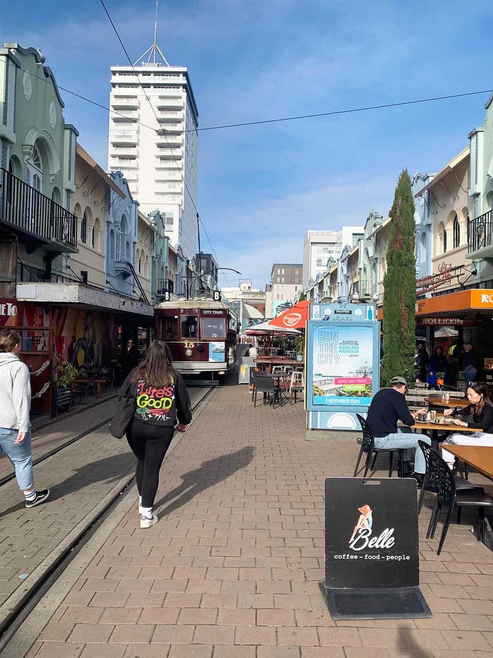 Vibrant street in Auckland with tram, cafes, and pedestrians, showcasing urban city life and popular tourist destinations.